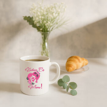 Kubek z kawą na stole, obok kwiatów i croissanta