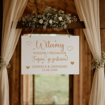 Drewniana tablica powitalna w aranżacji z kwiatami i girlandą – styl rustykalny
