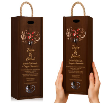 Brązowe pudełko prezentowe na wino z motywem obrączek i złotym napisem, trzymane w dłoniach