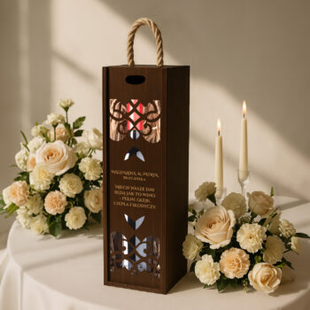 Eleganckie pudełko na wino z kwiatowym motywem ustawione na stole obok białych róż i zapalonych świec