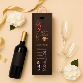 Pudełko na wino z motywem kwiatowym i grawerem ślubnym, ułożone na tle butelki wina, kieliszków i białego kwiatu.