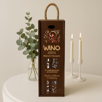 Eleganckie brązowe pudełko na wino ustawione na stole obok zielonej rośliny i dwóch świec